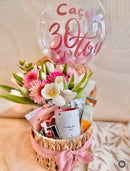 Cesta de presente de aniversário com balão e flores, da OhSurpriseGifts, decorada com flores coloridas e balão festivo.